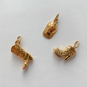 Detailansicht goldbeschichteter Stiefel- und Kappen-Anhänger mit poliertem Metallglanz