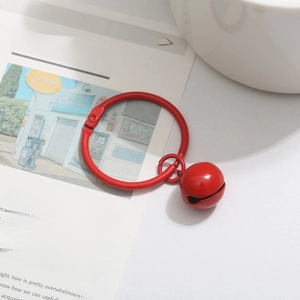 Detail of red metal bell charm with large snap ring on vintage newspaper background