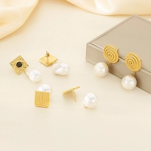 Golden spiral and evil eye square earrings with baroque pearls on beige silk fabric