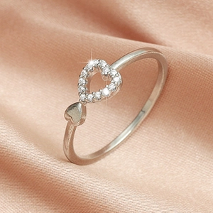 Macro shot of silver open ring with pavé heart and miniature heart detail on silk