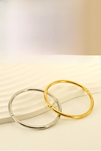 Detail of minimalist stainless steel bangles featuring gold and silver finishes and hidden clasp