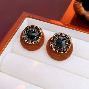 Close-up of retro square earrings with black gemstone and golden embossed metal frames