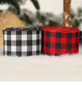 Close-up of red and black buffalo plaid Christmas ribbons with wired edges on snowy background
