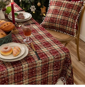Detail of Christmas red and green plaid table runner with snowflakes and white pompom trim