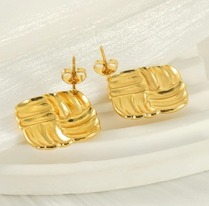 Detailed view of square textured 18k gold earrings with a stylish metallic pleated finish