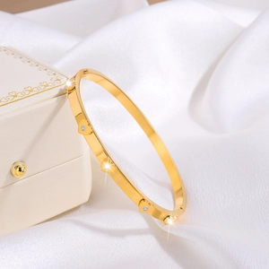 Detailed close-up of golden heart-shaped bangle with small rhinestones on silk