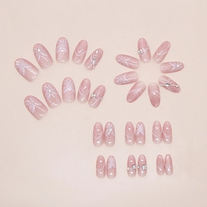 Flat lay of pink cat eye press-on nails with white butterfly patterns and rhinestones