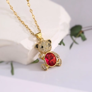 Golden necklace with teddy bear pendant set with red gems and zircons on white stone