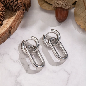 Macro detail of silver tone dual-link earrings on a luxury marble background