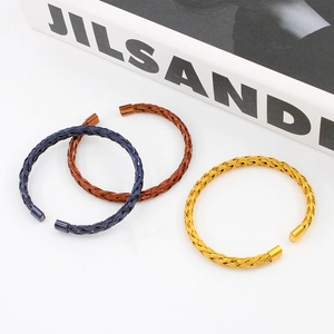 Macro detail of braided mesh cuff bracelets in blue, bronze, and gold metallic finishes