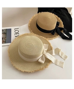 Flat top straw sun hats with frayed edges and bow ribbons on a stylish fashion magazine