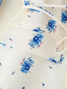 Detailed macro view of cream floral blazer fabric with blue flower patterns and waist tie