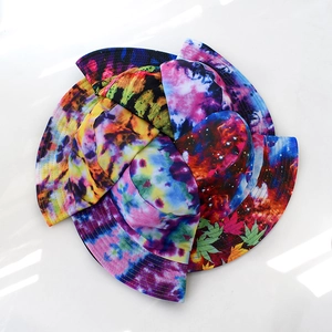 Top view of colorful starry sky and tie-dye bucket hats arranged in a creative circle
