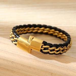 Detail of gold metal chain and black braided leather bracelet with a magnetic clasp