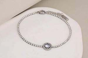 Close-up of silver tennis bracelet with a round blue stone and adjustable lobster clasp