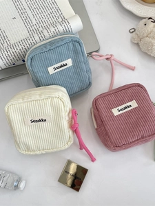 Corduroy makeup bags in blue, white, and pink with zipper closure and woven label