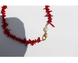 Detailed macro of red coral stone necklace with white pearl and golden lobster clasp