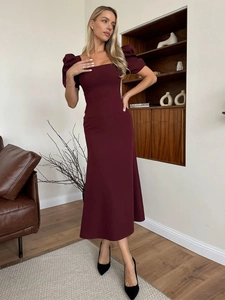 Detail of burgundy square neck dress with puff sleeves in a cozy home setting
