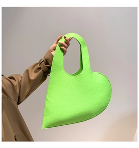 Detail of neon green heart-shaped felt handbag with reinforced stitching and modern cut