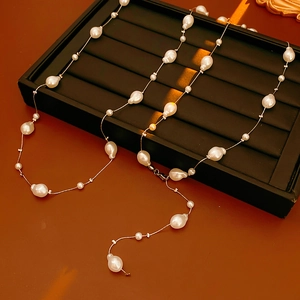 Détail de perles baroques sur chaîne en argent posées sur un plateau noir
