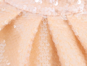 Macro shot of champagne sequin fabric texture on a luxury halter sleeveless evening gown