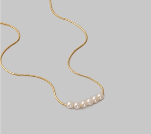 Minimalistische 18K Gold Perlenkette mit sechs weißen Perlen an einer schmalen Goldkette