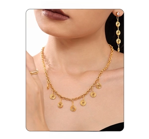 Close-up of golden spiral pendant necklace and matching tassel earrings on a model