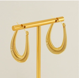 Detail of gold U-shaped hoop earrings with spiral texture on a metal T-stand display