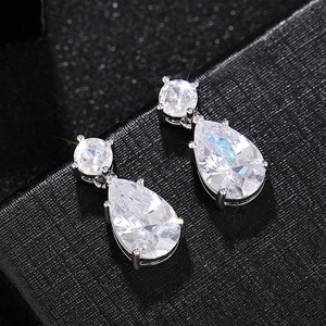 Vue macro de boucles d'oreilles scintillantes en zircone poire avec monture en argent