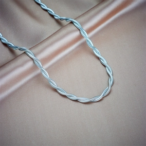 Sleek silver twisted chain necklace with a metallic spiral texture on champagne silk fabric