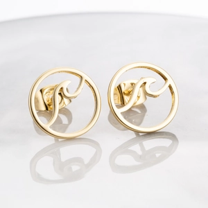 Macro detail of polished gold circle stud earring featuring internal wave pattern and reflection