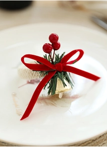 Christmas napkin ring with red velvet bow berries and pine needles on a white plate