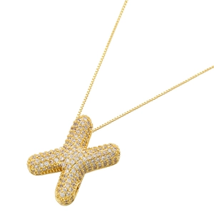 Close-up of golden X-shaped balloon letter pendant with sparkling pavé zircons
