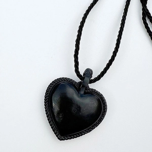 Détail du pendentif cœur noir avec texture tressée et son cordon assorti élégant