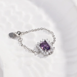 Detail view of purple rectangle gemstone ring with adjustable silver chain and heart charm