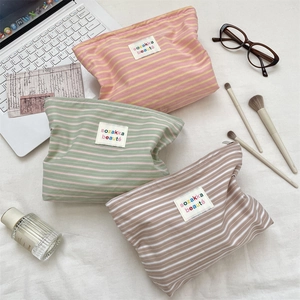 Flat lay of striped fabric cosmetic bags in various colors with laptop and makeup brushes