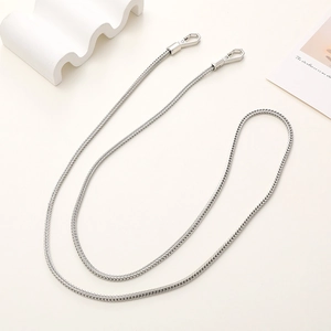 Detail of silver metallic bag chain with snap hooks on a minimalist white background