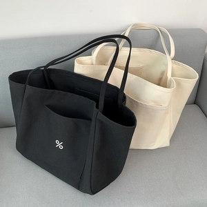 Detail shot of black and beige canvas tote bags with side pockets on a sofa