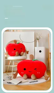 Macro detail of plush red apple cushions with cute embroidered faces in a cozy home setting