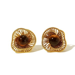 Détail de boucles d'oreilles vintage avec pierre œil de tigre et spirales dorées ajourées