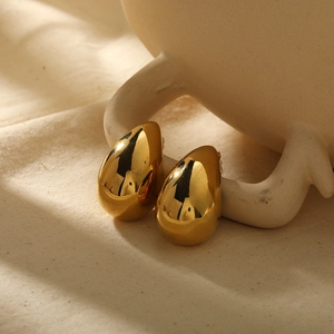 Vue macro des boucles d'oreilles goutte d'eau dorées polies sur fond en tissu doux