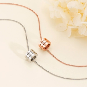 Close-up of silver and rose gold cylinder pendants with diamond accents and floral decor