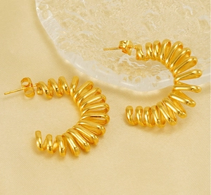 Détail de boucles d'oreilles spirales en C dorées avec finition polie sur tissu