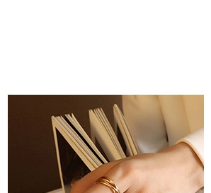 Detail of 18K gold plated triple layered intertwined ring worn by a model reading