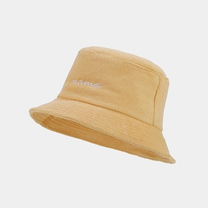 Detailed view of the yellow terry cloth bucket hat with white mama script embroidery