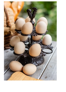 Détail du porte-œufs vintage en fonte avec poignée coq dans une cuisine rustique