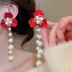Detail of red flower earrings with pearls and rhinestones on elegant model