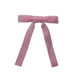 Detalle de pasador de pelo con lazo doble de terciopelo rosa y cintas largas colgantes