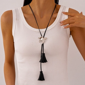Detail of a black tassel necklace with silver bird-shaped metallic pendant on a model