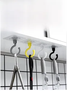 Close-up of four colorful rotating ceiling hooks holding kitchen tools under a cabinet